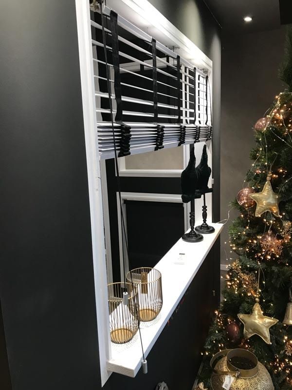 Im Hintergrund ist ein Weihnachtsbaum und ein Fenster mit Jalousien.