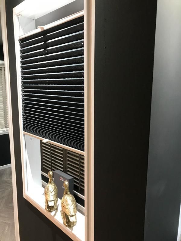 Ein Fenster mit Jalousien und einem Regal mit zwei Buddhastatuen darauf.