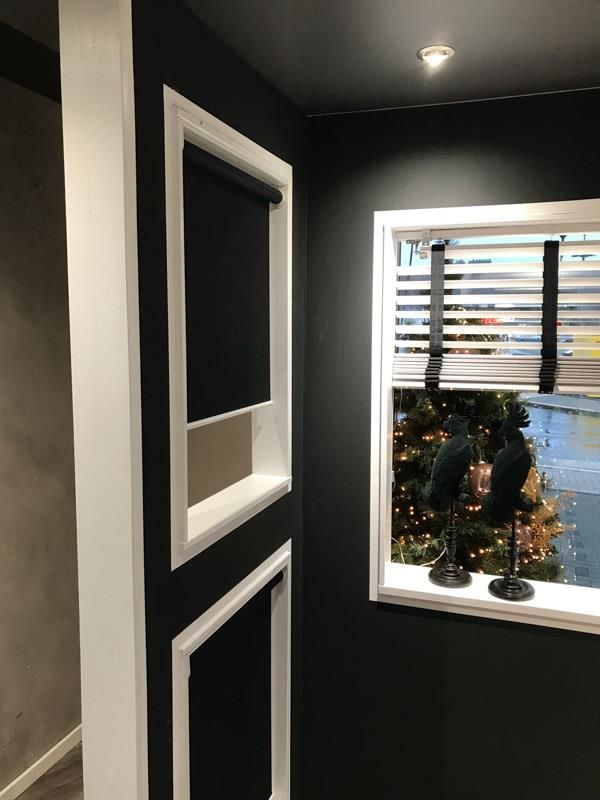 Es gibt ein Fenster mit Jalousien und im Hintergrund einen Weihnachtsbaum.