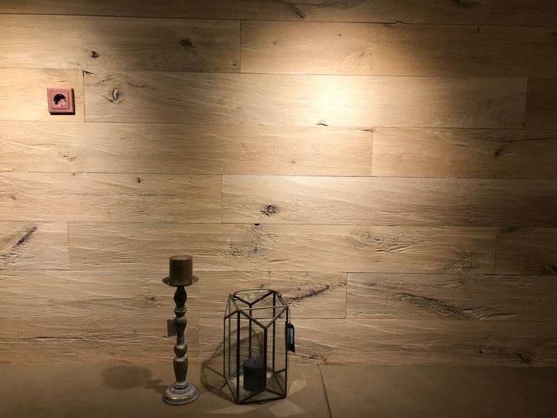 Ein Kerzenhalter und eine Laterne stehen auf einem Holzboden vor einer Holzwand.