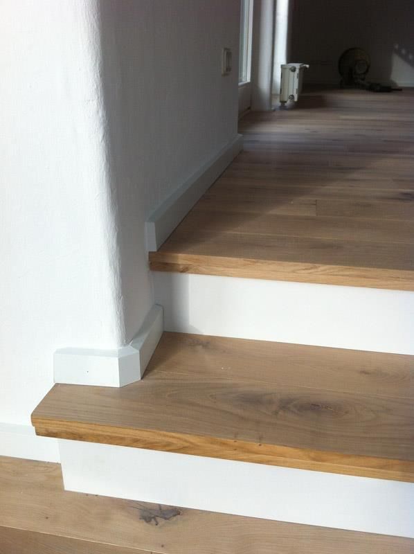Eine Holztreppe mit weißen Zierleisten und einem Holzboden