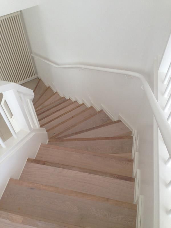 Die Treppe ist aus Holz und hat ein weißes Geländer.