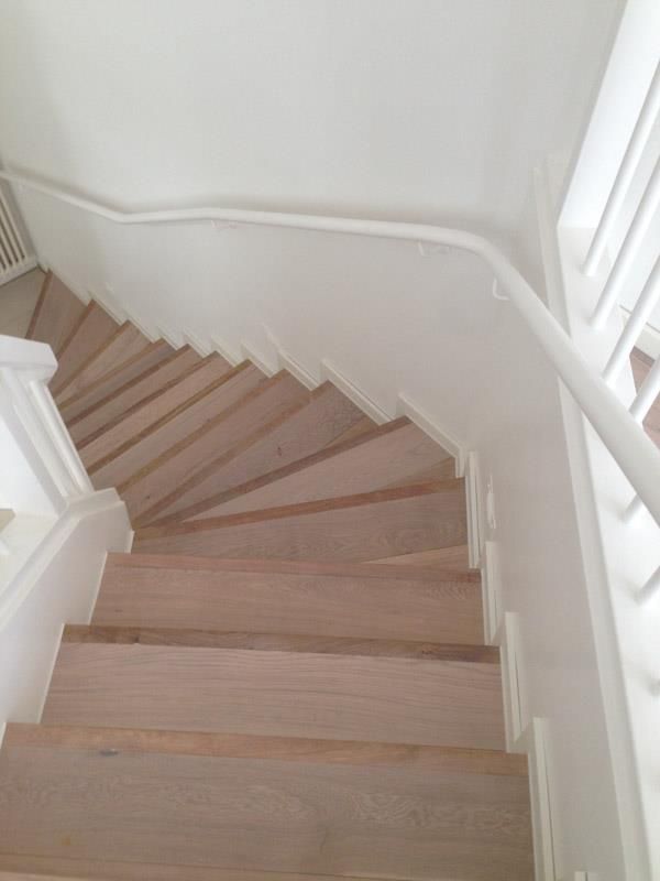 Die Treppe ist aus Holz und hat ein weißes Geländer.