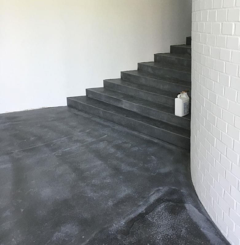 Eine Treppe führt zu einer weißen Backsteinmauer hinauf.