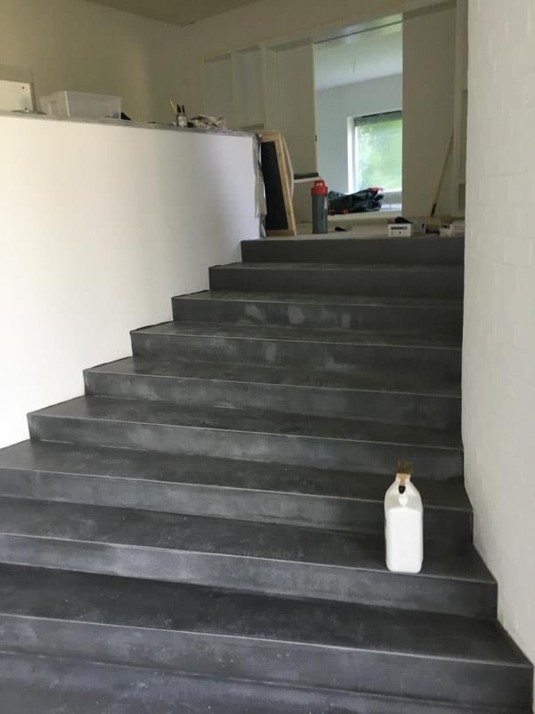 Am Fuß einer Treppe steht eine weiße Flasche.