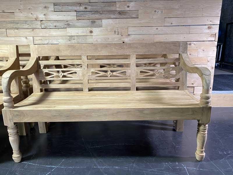 Vor einer Holzwand steht eine Holzbank.