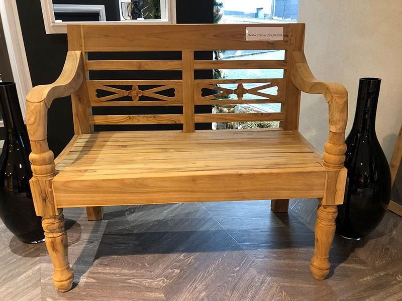 Auf einem Holzboden steht neben Vasen eine Holzbank.