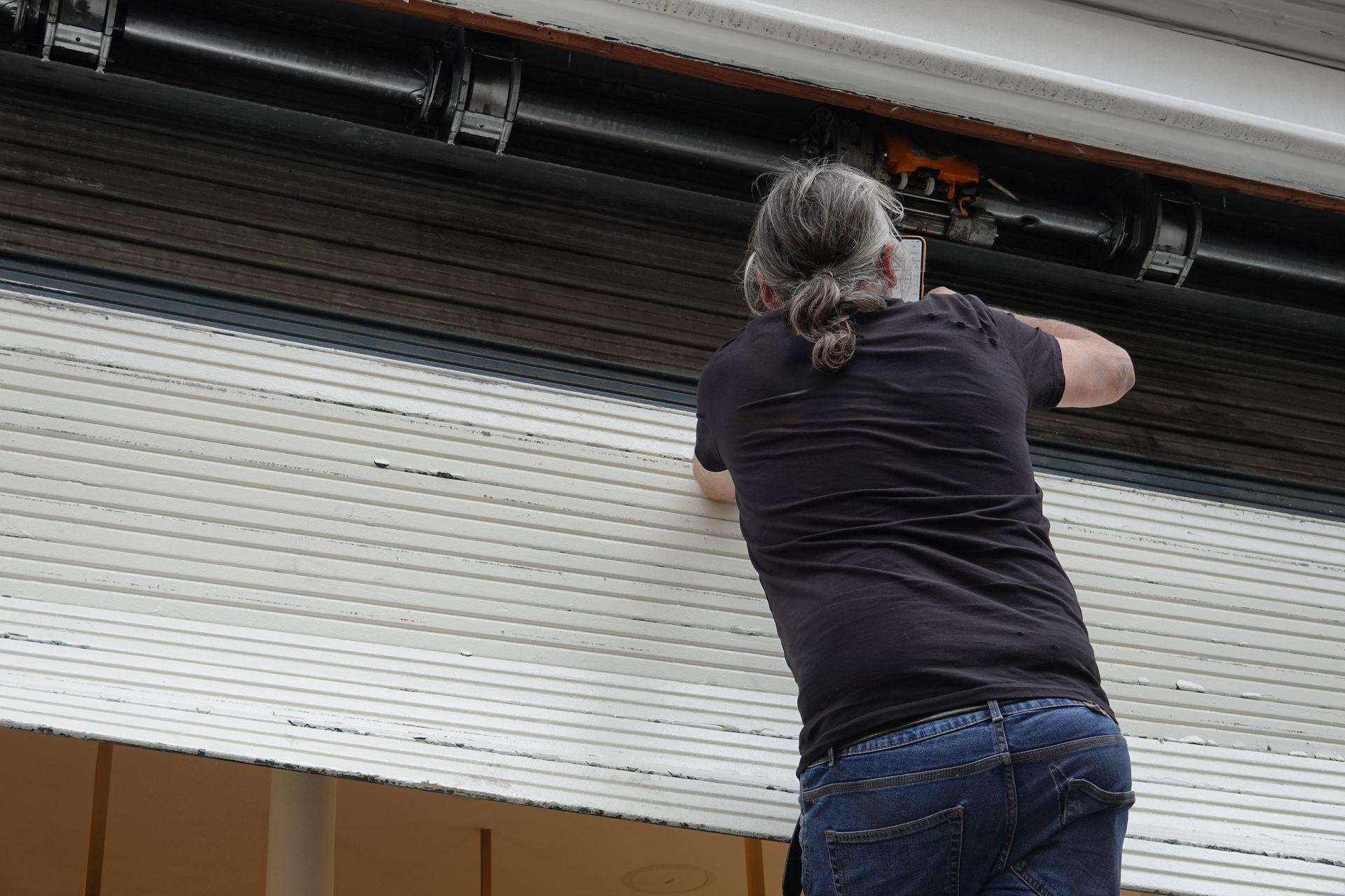 Personne qui ouvre une porte de garage métallique à enroulement dans un entrepôt