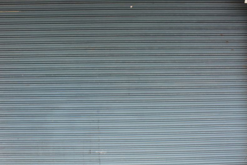 Rideau métallique gris à rayures horizontales, avec une petite tache sombre près du centre