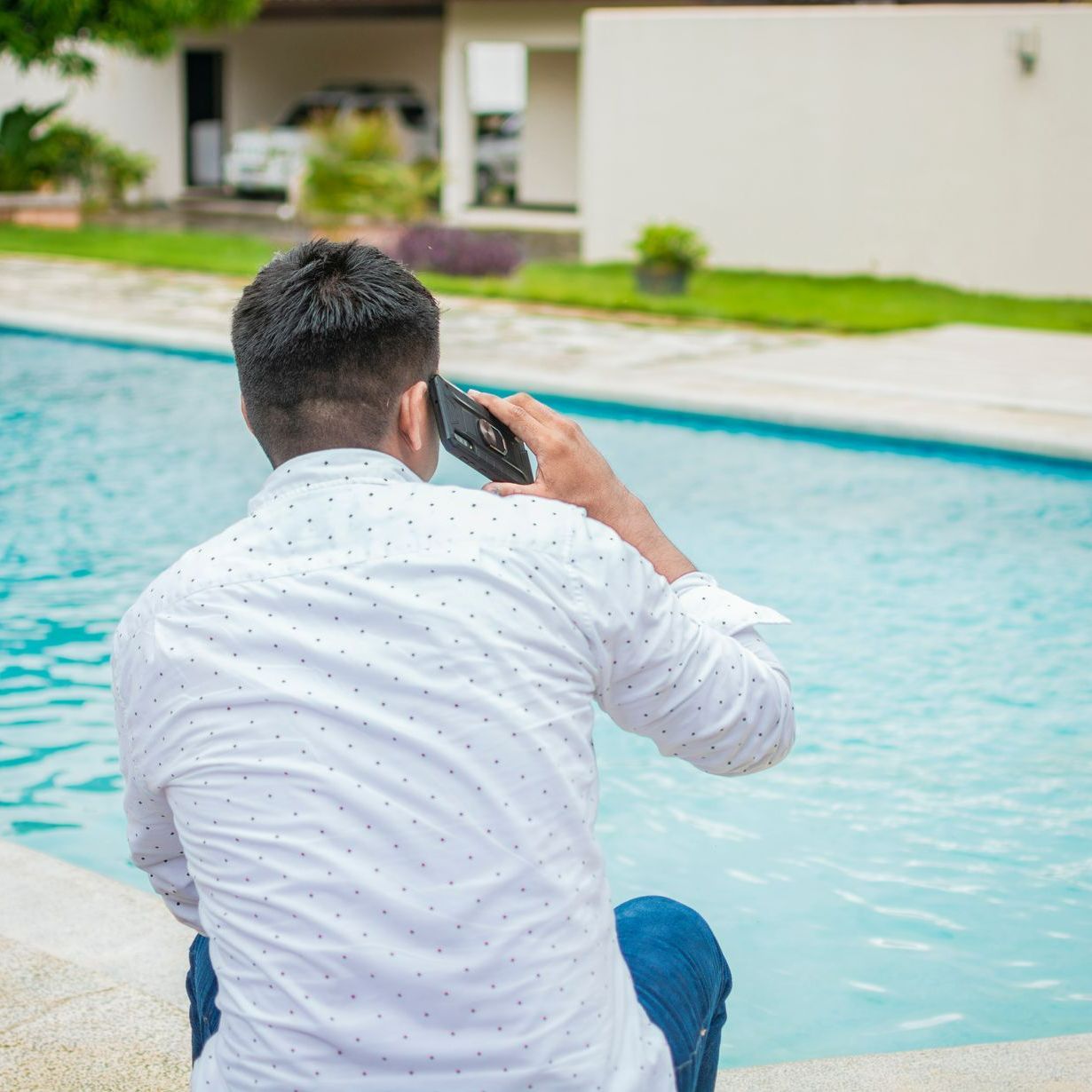 Homme au téléphone devant une piscine