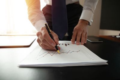 Ein Mann schreibt mit einem Stift auf ein Blatt Papier.