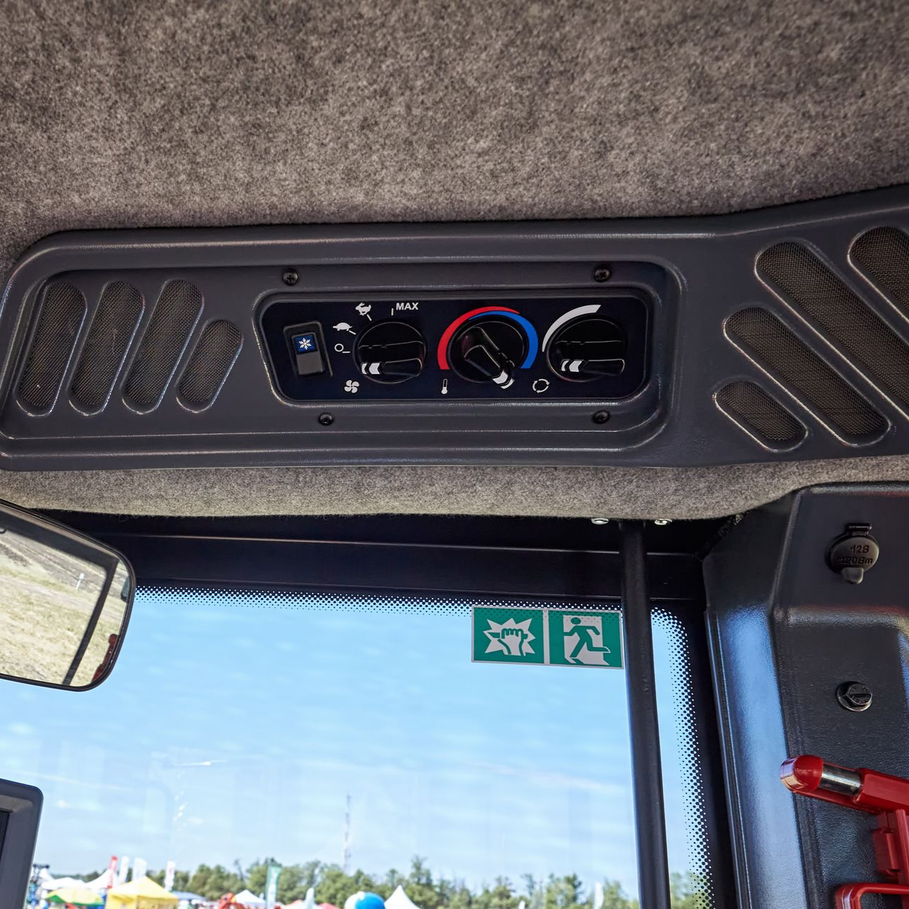 Panneau de commande dans la cabine du véhicule, comportant les commandes de climatisation, au-dessus d'une fenêtre avec un panneau de sortie.