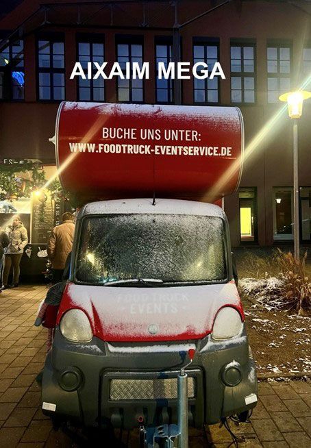 Vor einem Gebäude parkt ein rot-weißer Imbisswagen.