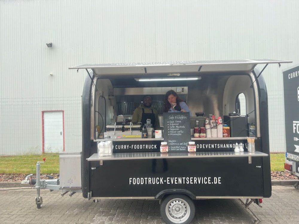 Vor einem Gebäude parkt ein Imbisswagen.