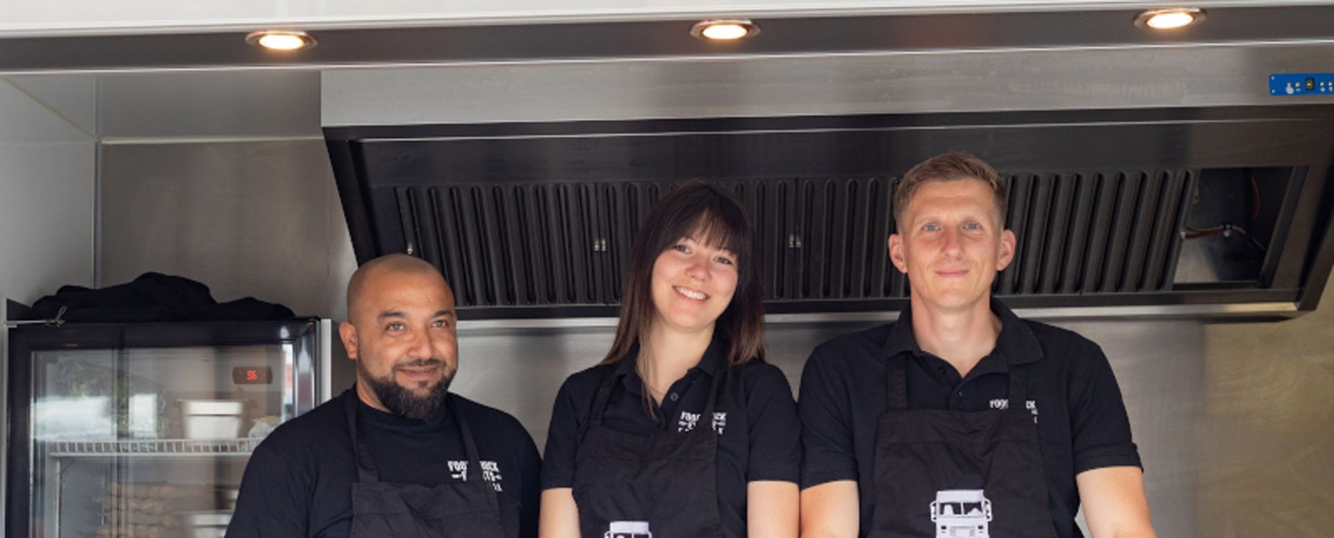 Ein Mann und zwei Frauen stehen nebeneinander in einer Küche.