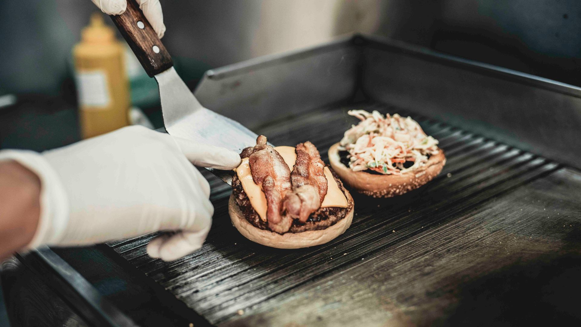 Eine Person brät einen Hamburger auf einem Grill.
