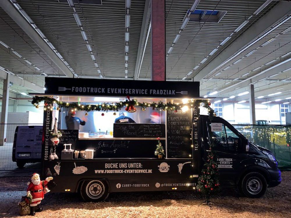 In einer Lagerhalle wird ein Imbisswagen weihnachtlich dekoriert.