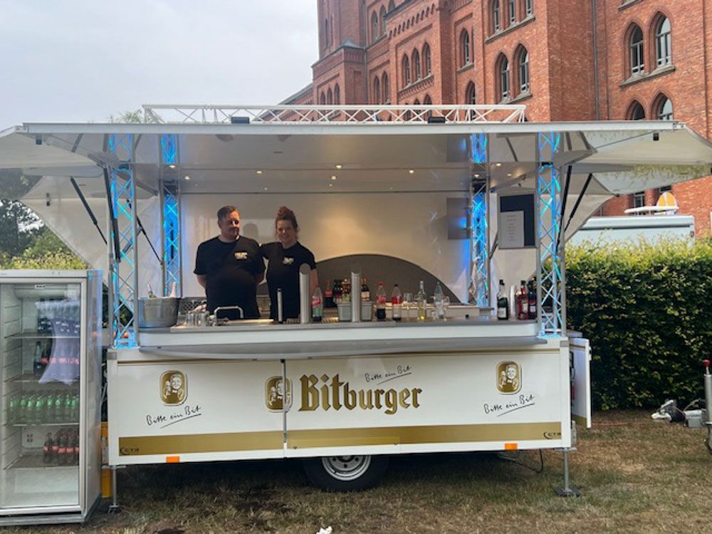 Vor einem Backsteingebäude parkt ein Imbisswagen.