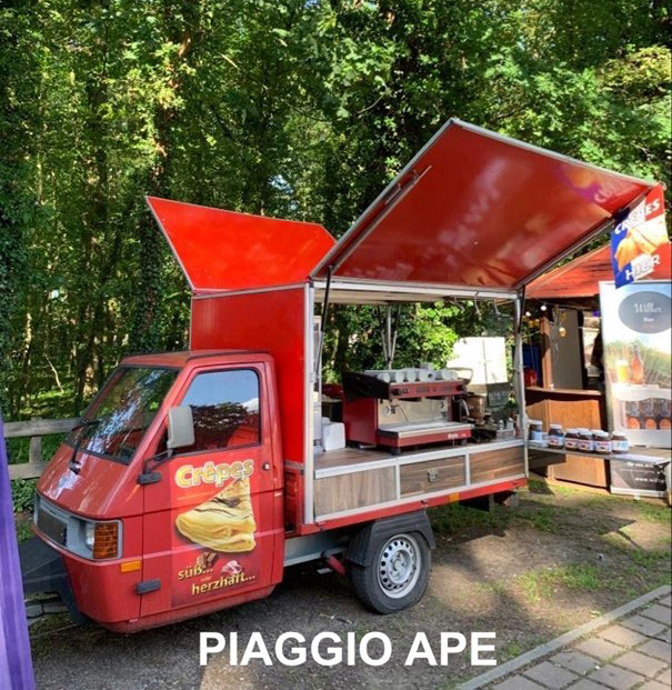 Ein roter Piaggio Ape Food Truck steht im Wald