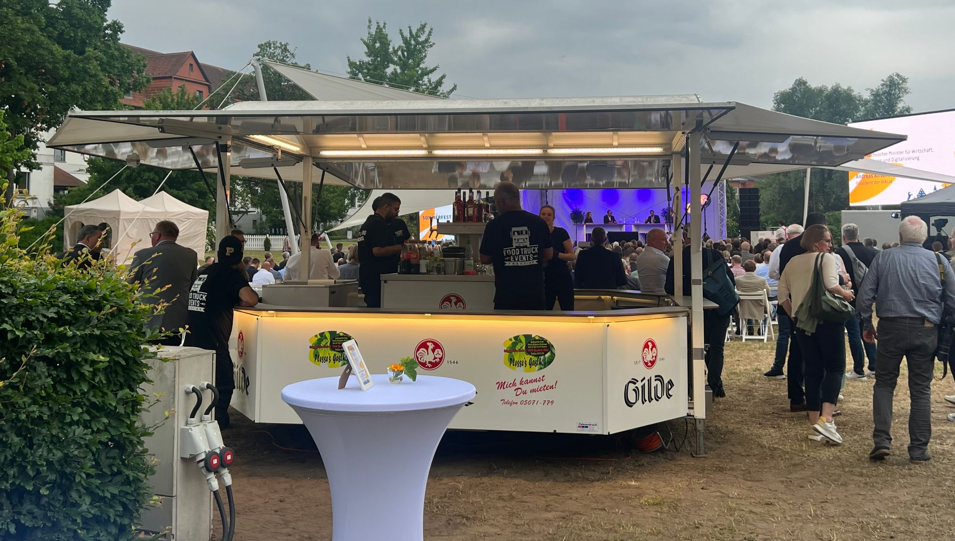 Am Straßenrand parkt ein Imbisswagen, hinter dem zwei Männer stehen.