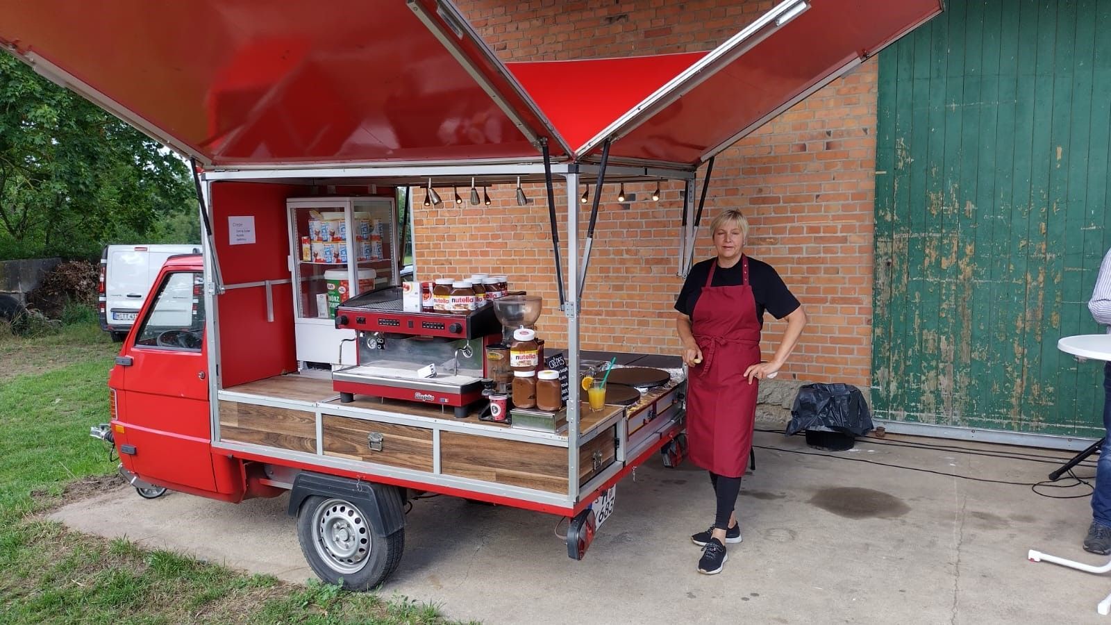 Eine Frau steht vor einem roten Imbisswagen.