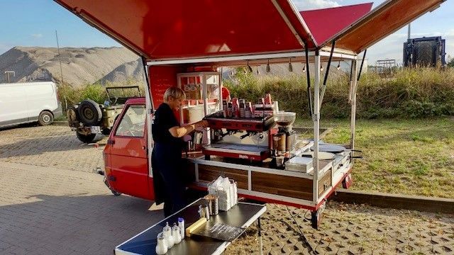 Ein Mann steht vor einem roten Imbisswagen.