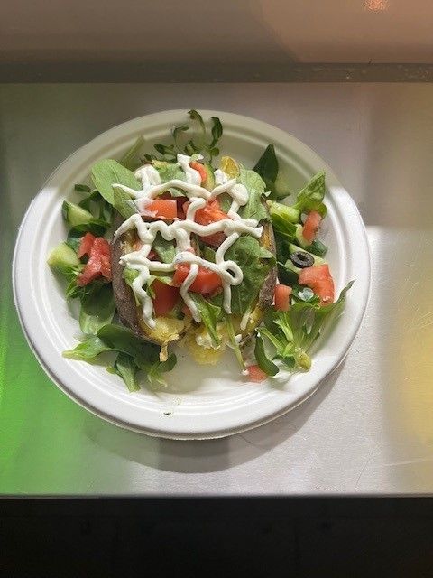 Ein weißer Teller mit Salat und Mayonnaise auf einem Tisch.