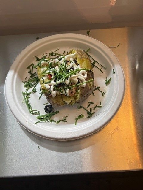 Ein weißer Teller mit einer Ofenkartoffel und Gemüse