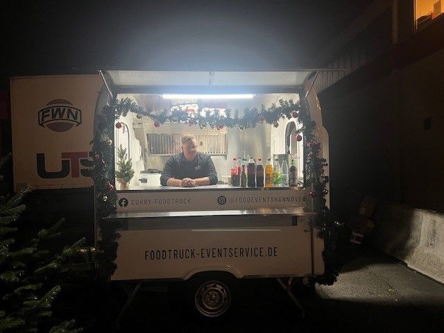 Ein Mann steht nachts vor einem Imbisswagen.