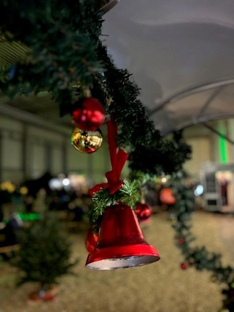 An einem Weihnachtsbaum hängt eine rote Glocke.