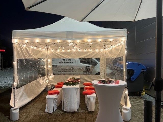 Ein weißes Zelt mit einem Tisch und Stühlen darunter