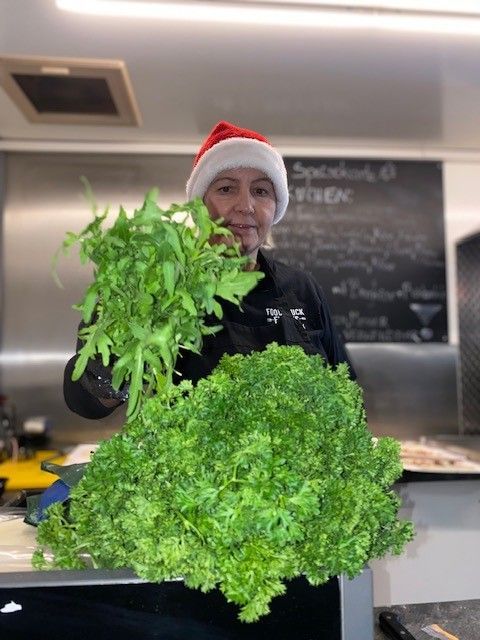 Eine Frau mit Weihnachtsmannmütze hält einen großen Bund Salat in der Hand.