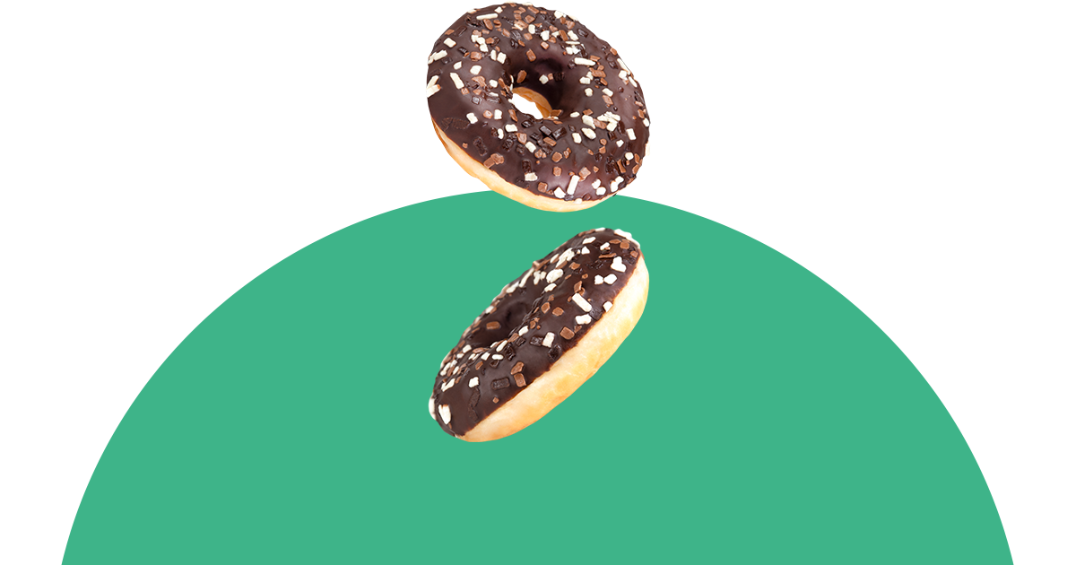Zwei Schokoladendonuts fallen auf eine grüne Oberfläche.