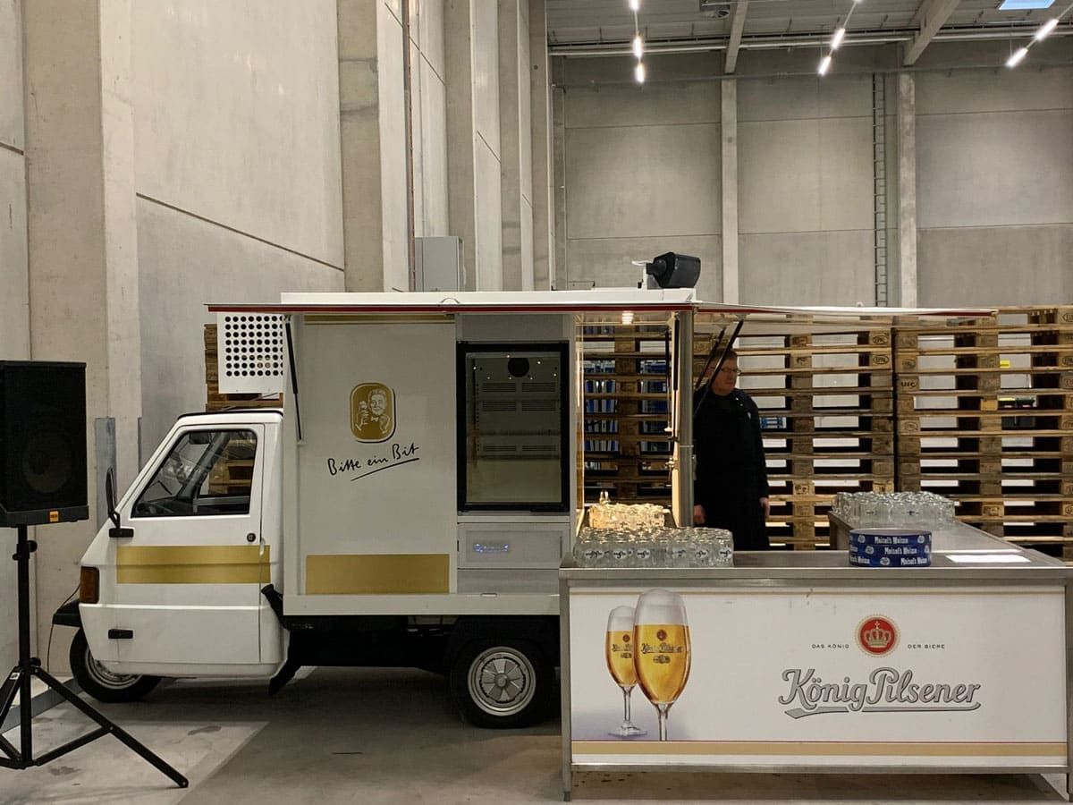 Ein weiß-goldener Imbisswagen steht in einem Lagerhaus.