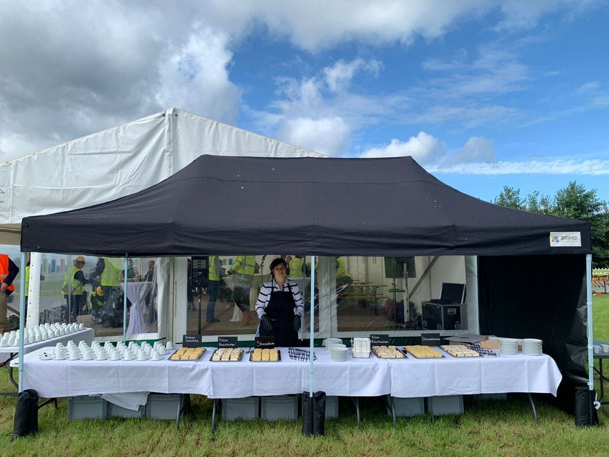 Eine Frau steht hinter einem Tisch unter einem Zelt.