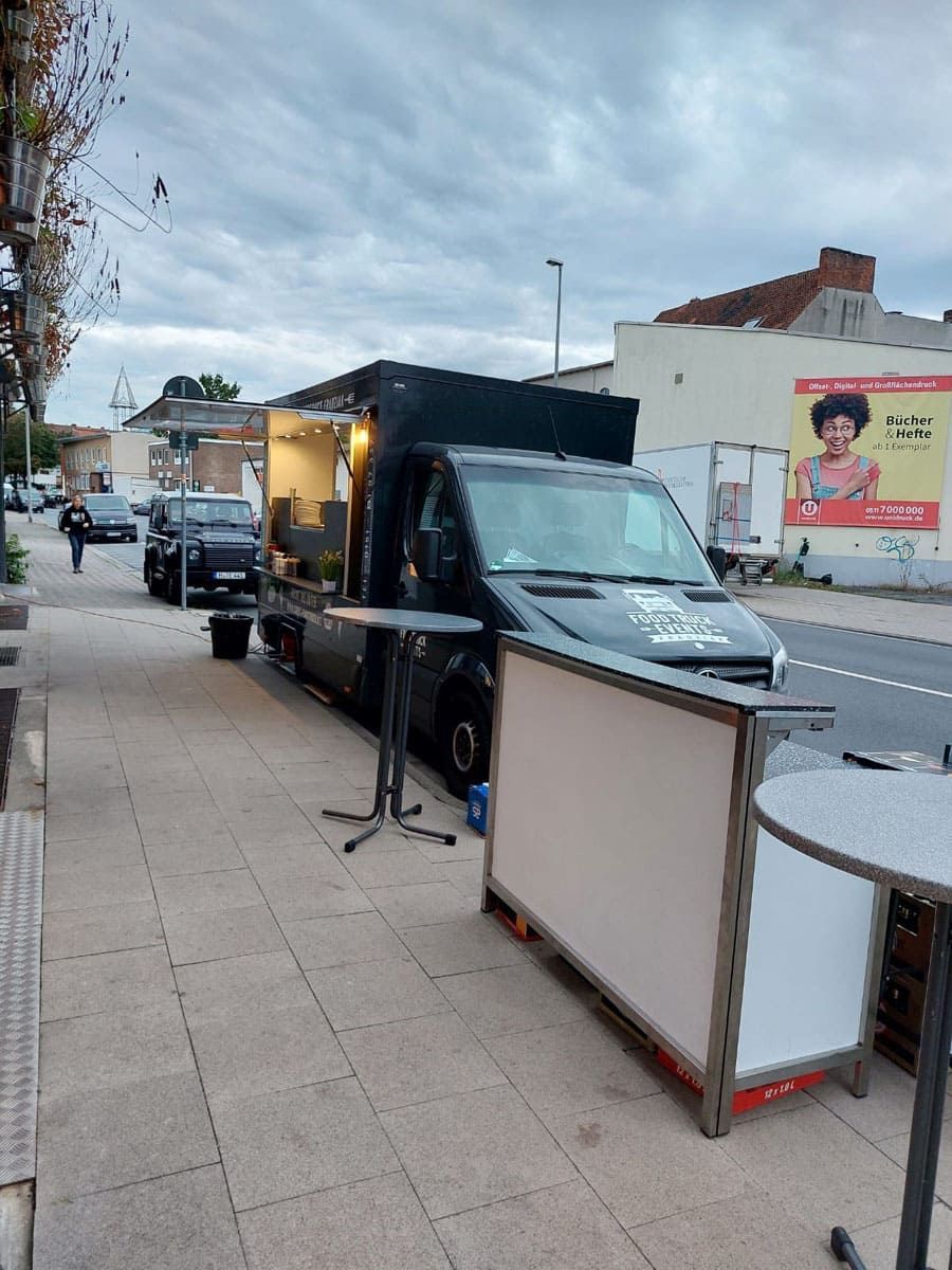 Ein Imbisswagen steht am Straßenrand neben einem Tisch.