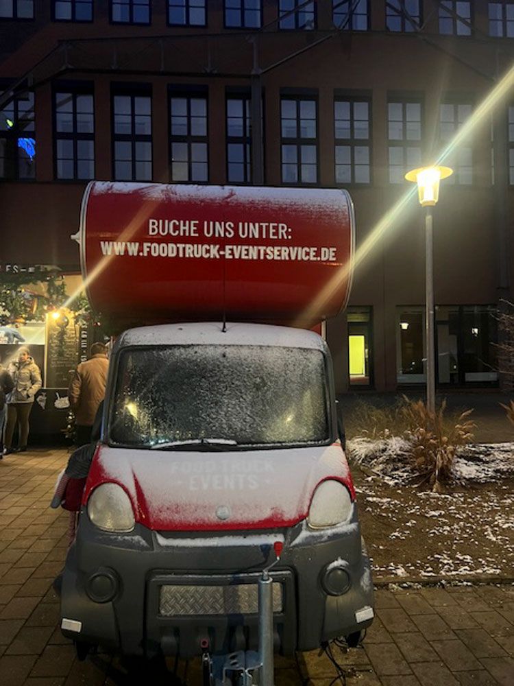 Ein Imbisswagen steht nachts vor einem Gebäude.