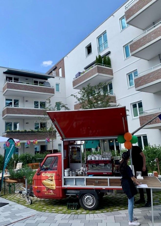 Vor einem Gebäude parkt ein roter Imbisswagen.