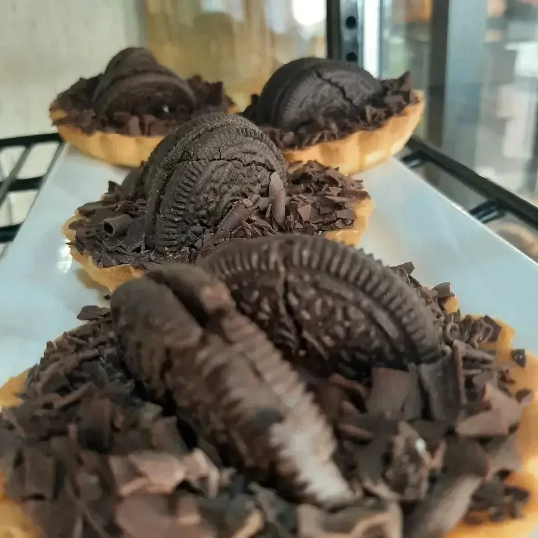 Tartas de galletas de chocolate en un plato blanco, cubiertas con virutas de chocolate y galletas.