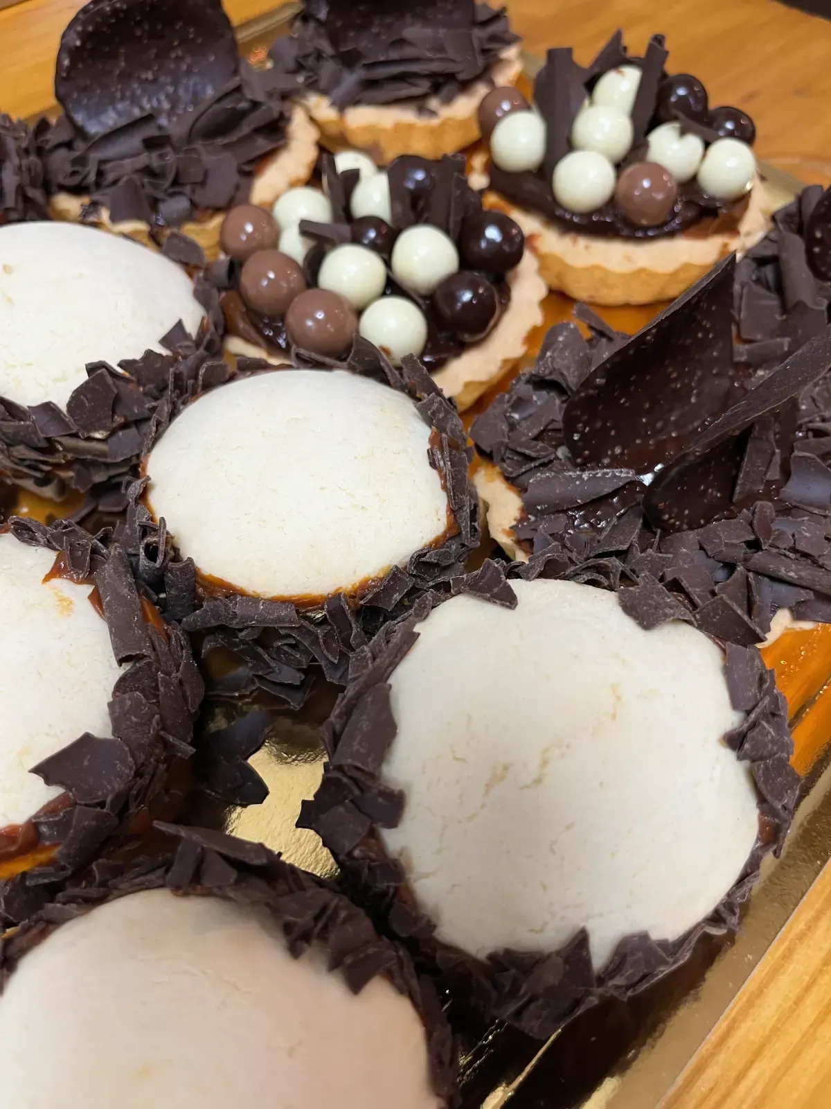 Primer plano de mini tartas surtidas. Algunas tienen glaseado blanco, otras de chocolate