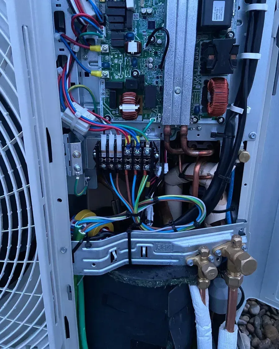 Unidad de climatización abierta, con el cableado, la placa de circuito, los tubos de cobre y las válvulas de servicio