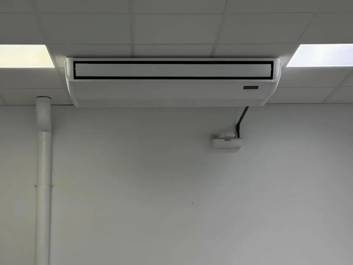 Aire acondicionado de techo en una pared blanca de una habitación sencilla