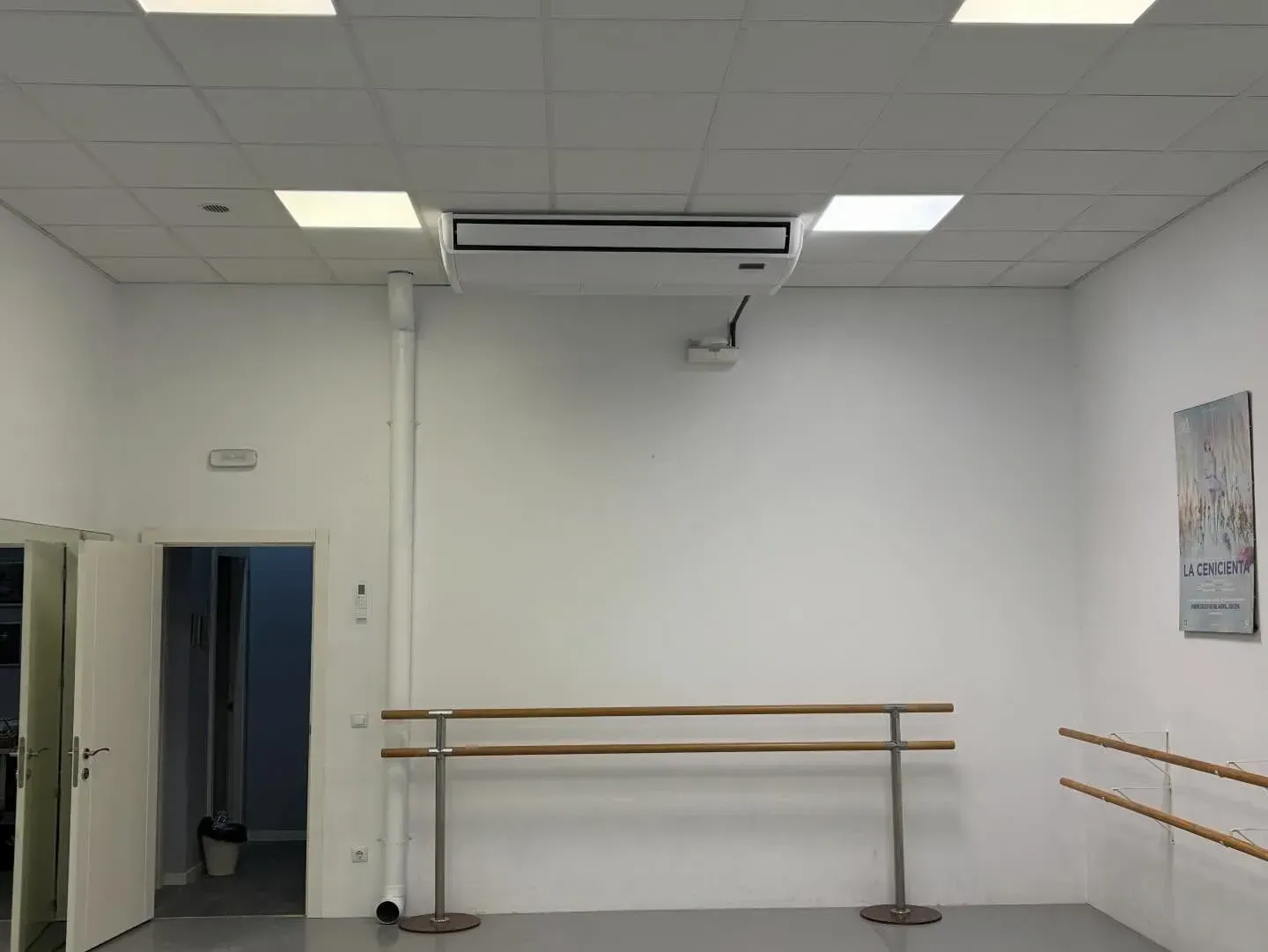 Estudio de danza vacío, con paredes blancas, espejos, barras de ballet de madera y luces en el techo