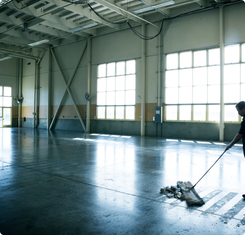Un homme nettoie le sol en béton d'un grand bâtiment