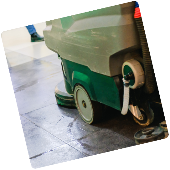 Une machine verte à roues nettoie un sol carrelé