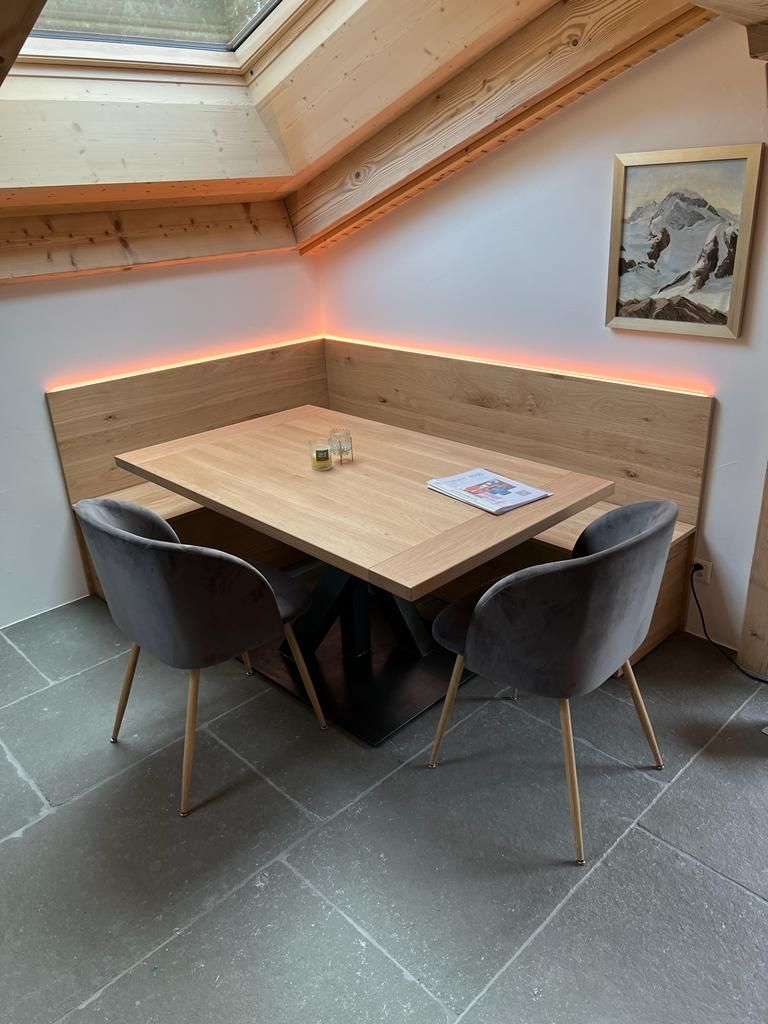 Eine Holzbank vor einem Fenster in einem Wohnzimmer. Foto von der Holzprofi Zermatt AG