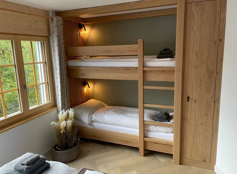 Ein Bett mit dem auf die Wand gemalten Matterhorn dahinter. Foto von der Holzprofi Zermatt AG