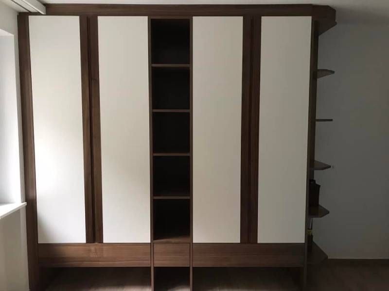 Ein braun-weisser Kleiderschrank mit Regalen und Schubladen in einem Zimmer.  Foto von der Holzprofi Zermatt AG