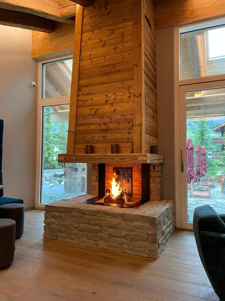 Ein Schlafzimmer mit grossem Bett und Holzwand. Foto von der Holzprofi Zermatt AG