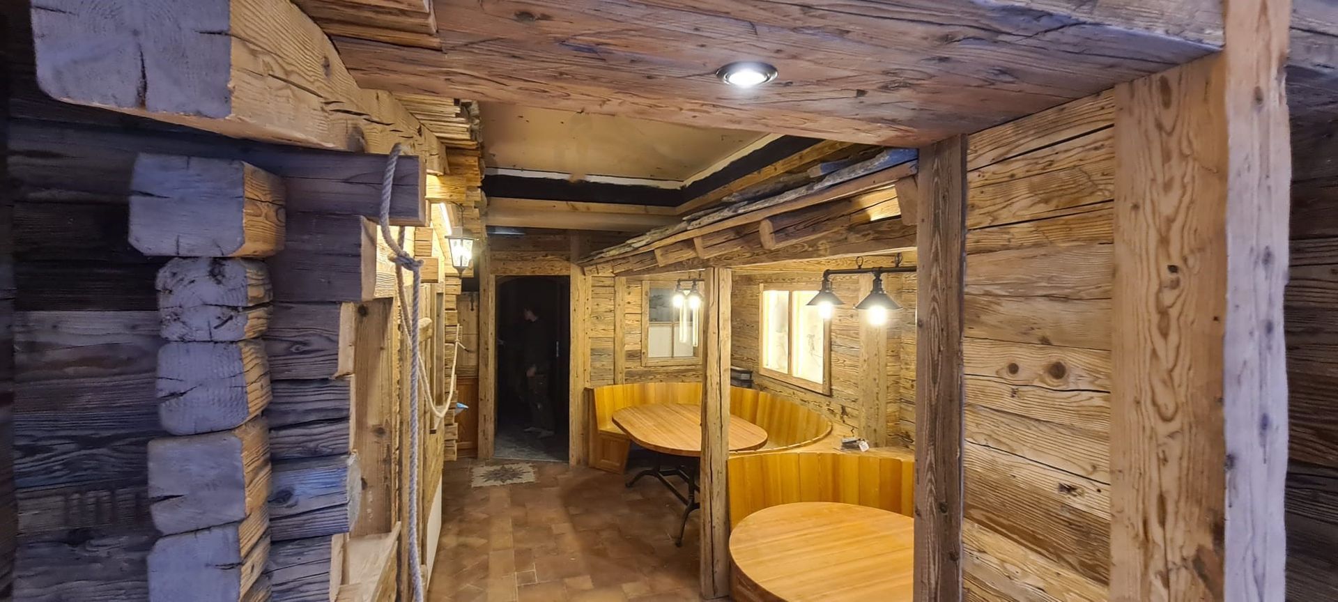 Ein Wohnzimmer mit Tisch und Stühlen und einem Bild an der Holzwand. Foto von der Holzprofi Zermatt AG